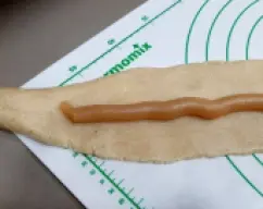 Step <p>Precalienta el horno a 180º</p><p><br></p><p>Ahora rellena del dulce de boniato, ayudándote con la manga pastelera o a cucharaditas. Cierra como si cerrases un monedero antiguo ? y así quedará todo sellado el relleno. Dale la vuelta al rulo, de manera que esa parte quede abajo.</p> illustration