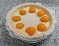 Step <p>Colocamos por encima de la crema pastelera las rodajas de melocotón, colocándolas a la altura de los cortes que previamente hemos hecho.</p><p><br></p> illustration