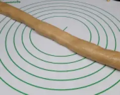 Step <p> A continuación, dale forma de rodillo largo, de unos 50cm. Puedes ir apretando la masa con las manos, a la vez que vas estirando hacia adelante y hacia atrás, pues la masa no es como la del pan no es elástica y pueden abrirse grietas. Si lo necesitas, puedes humedecerte las manos en agua.</p> illustration
